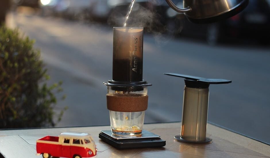 Aeropress coffee maker in use with a glass mug, scale, and kettle, illustrating useful Aeropress accessories for home brewers.
