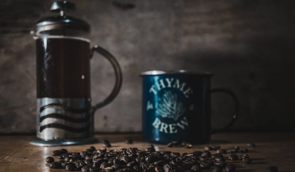 A cozy scene featuring a French press, a mug labeled 'Thyme for Brew', and coffee beans on a wooden table.