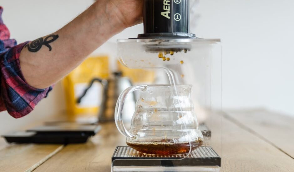 A person uses an AeroPress to brew espresso-style coffee into a glass carafe, illustrating the AeroPress vs French Press comparison.