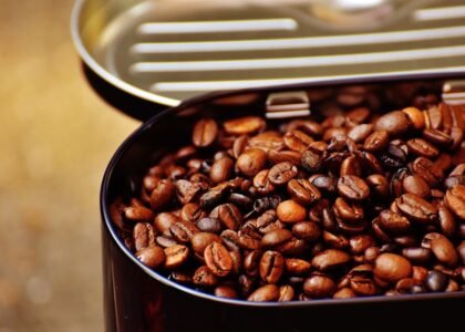 Close-up of roasted coffee beans in an open metal container, highlighting texture.
