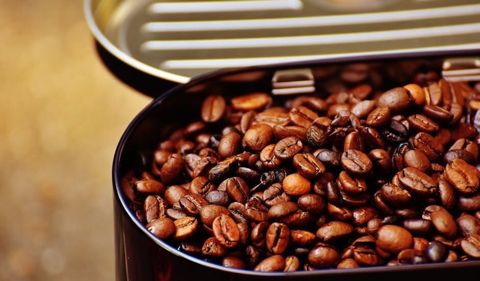 Close-up of roasted coffee beans in an open metal container, highlighting texture.