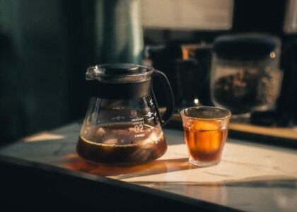 A glass coffee server carafe filled with brewed coffee and a matching glass cup, illustrating top carafe options.