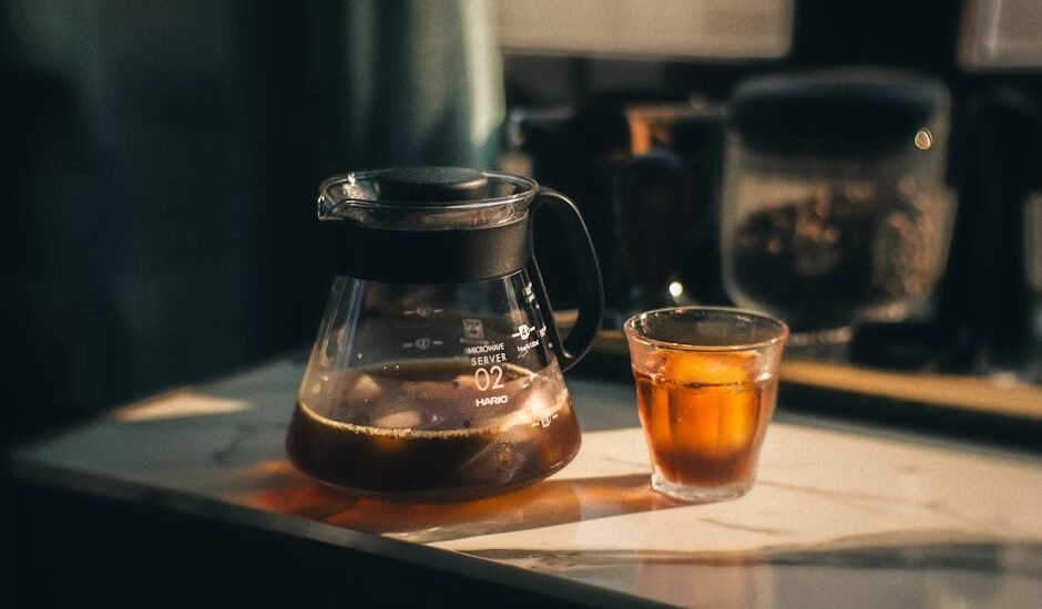 A glass coffee server carafe filled with brewed coffee and a matching glass cup, illustrating top carafe options.