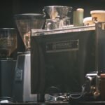 Close-up of an espresso machine in a cafe with coffee grinders and cups.
