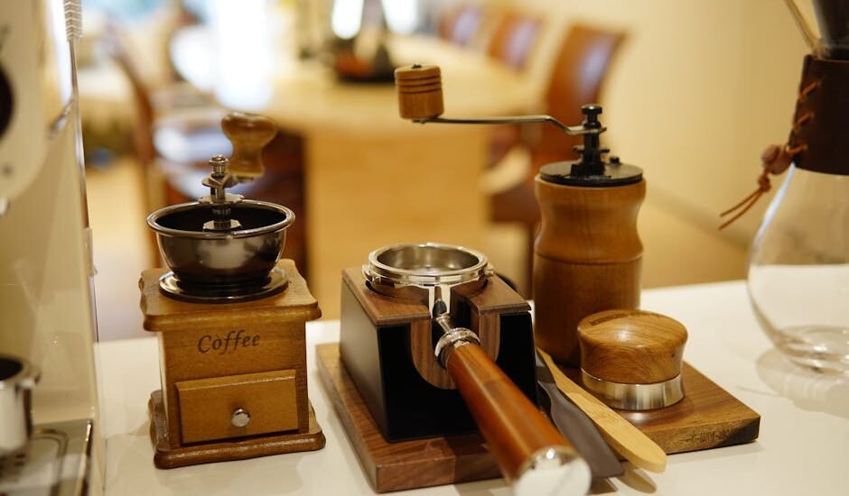 Selection of home barista accessories including manual coffee grinders, a tamper, and a portafilter on a kitchen counter.