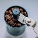 Close-up of a manual burr grinder filled with coffee beans, illustrating parts to check when finding replacement components.