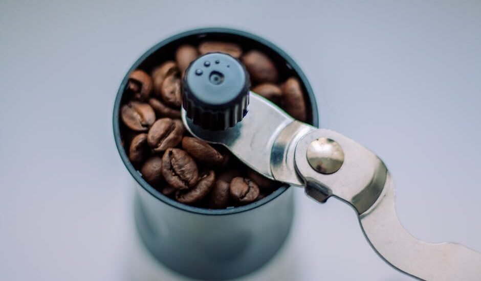 Close-up of a manual burr grinder filled with coffee beans, illustrating parts to check when finding replacement components.