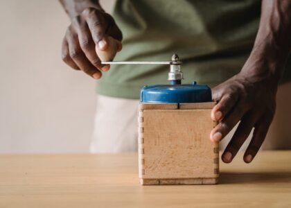 Person using a manual burr coffee grinder, illustrating the difference between burr and blade grinders for espresso.
