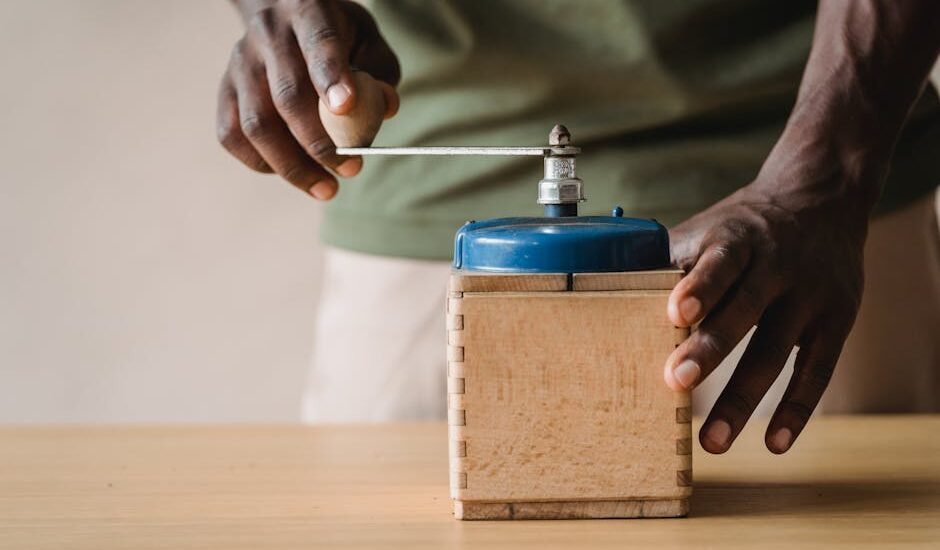 Person using a manual burr coffee grinder, illustrating the difference between burr and blade grinders for espresso.