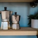Two moka pots of different sizes on a wooden shelf, illustrating the moka pot side of the espresso machine vs moka pot comparison article