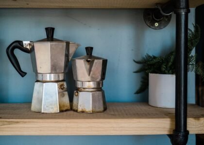 Two moka pots of different sizes on a wooden shelf, illustrating the moka pot side of the espresso machine vs moka pot comparison article