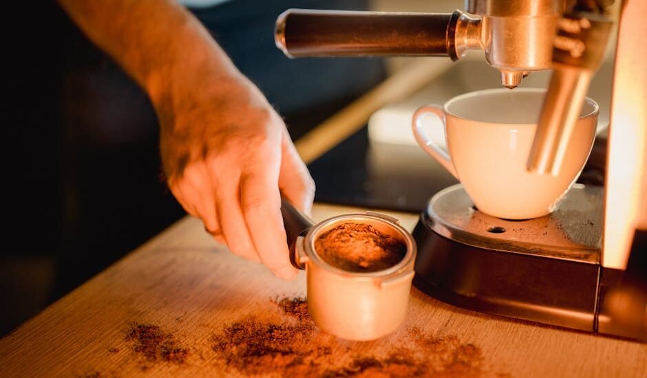 Close-up of a person loading ground coffee into a portafilter next to an espresso machine, highlighting water filter use.