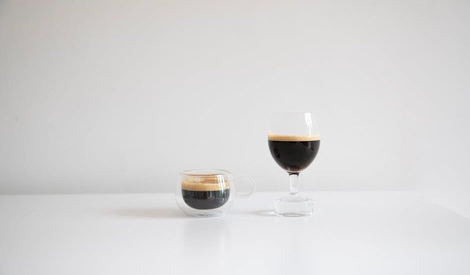 Two espresso shot glasses, one small and one larger, filled with espresso, relevant to espresso shot glasses for machines.