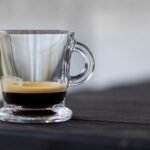 A clear glass cup of espresso with a visible layer of crema, illustrating the science behind espresso foam.