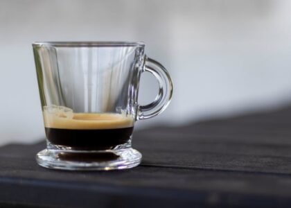 A clear glass cup of espresso with a visible layer of crema, illustrating the science behind espresso foam.