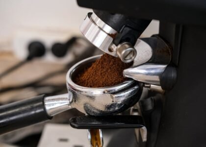 Close-up of an espresso grinder dispensing ground coffee into a portafilter, illustrating grind size adjustment for espresso preparation.
