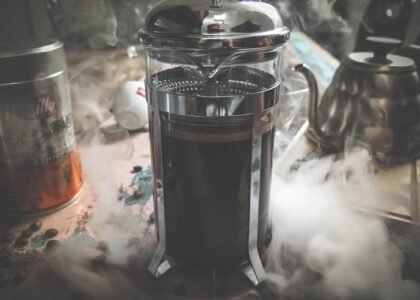 A steaming French press filled with coffee sits on a kitchen counter, illustrating how to preheat a French press for better coffee.