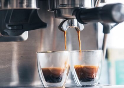 Close-up of espresso machine brewing two shots into glass cups, illustrating brew chamber age comparison topic