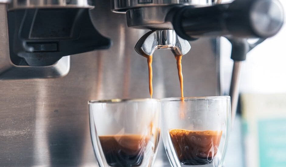 Close-up of espresso machine brewing two shots into glass cups, illustrating brew chamber age comparison topic