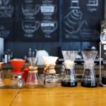 A lineup of various pour over coffee makers and drip brewers on a café counter, illustrating the differences discussed in the pour over vs drip coffee makers co