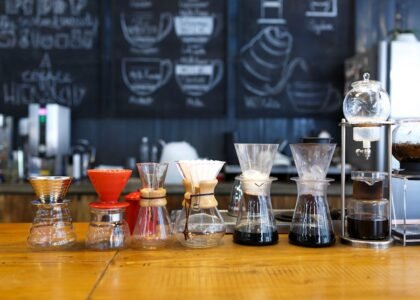 A lineup of various pour over coffee makers and drip brewers on a café counter, illustrating the differences discussed in the pour over vs drip coffee makers co