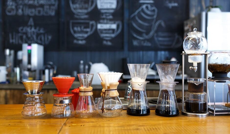 A lineup of various pour over coffee makers and drip brewers on a café counter, illustrating the differences discussed in the pour over vs drip coffee makers co