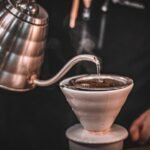 A gooseneck electric kettle pours hot water over coffee grounds in a dripper, illustrating top kettle choices for home brewers.