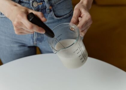 A person frothing milk in a measuring jug with an automatic milk frother, relevant to latte art.