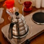 A stainless steel electric kettle on a brewing station, showcasing pour-over coffee gear.