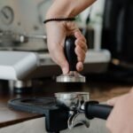 A hand using a tamper on an espresso tamping mat, illustrating the article on tamping mats.