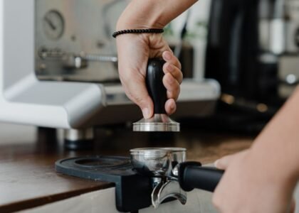 A hand using a tamper on an espresso tamping mat, illustrating the article on tamping mats.