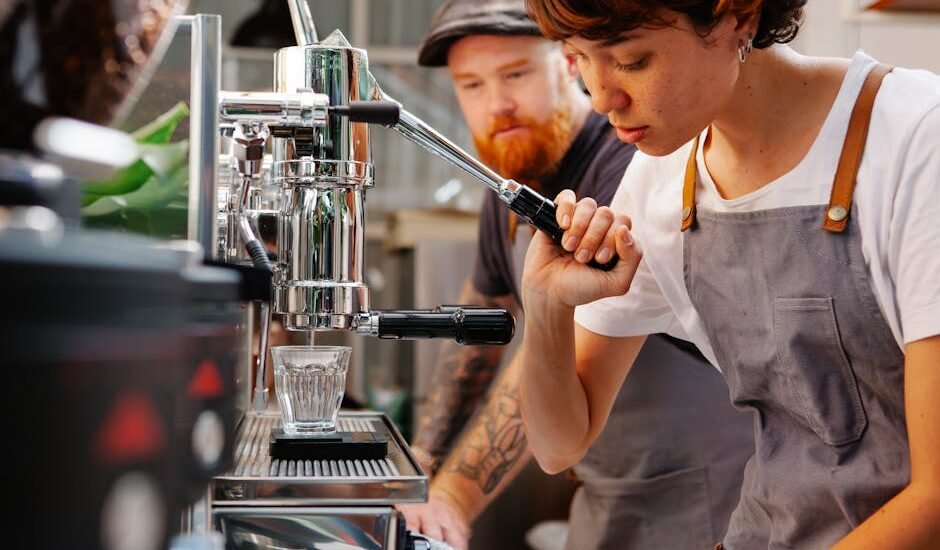 A person operating a manual espresso lever machine while another observes, illustrating the article on manual espresso levers.