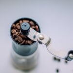 A manual coffee grinder filled with coffee beans, illustrating ceramic vs stainless steel grinders.