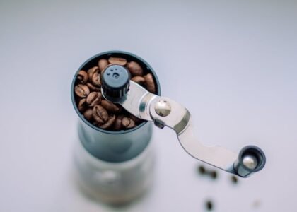 A manual coffee grinder filled with coffee beans, illustrating ceramic vs stainless steel grinders.