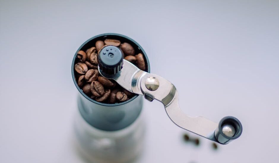 A manual coffee grinder filled with coffee beans, illustrating ceramic vs stainless steel grinders.