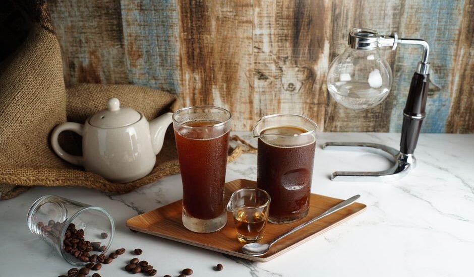 Cold brew maker setup featuring two glasses of cold brew coffee and coffee beans.