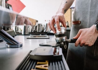 A person demonstrating the use of an espresso distribution tool on a portafilter.