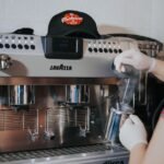 An espresso machine is steaming milk, illustrating warm-up times for brewing.