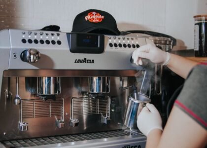 An espresso machine is steaming milk, illustrating warm-up times for brewing.