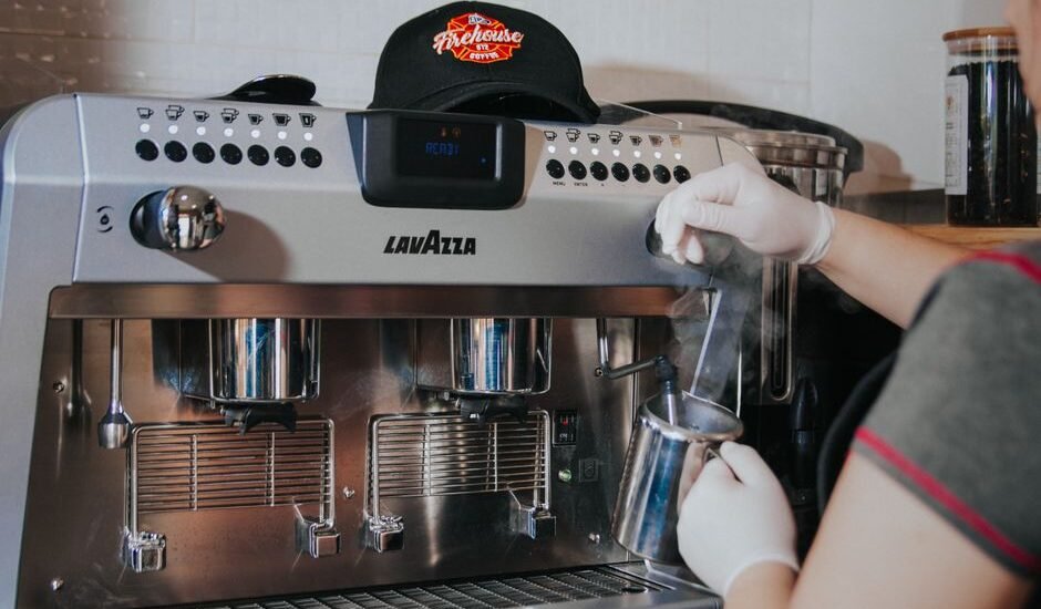 An espresso machine is steaming milk, illustrating warm-up times for brewing.