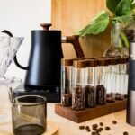 A hand grinder and electric grinder alongside coffee brewing gear, illustrating the article's topic.