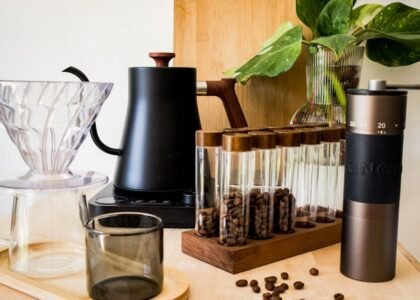 A hand grinder and electric grinder alongside coffee brewing gear, illustrating the article's topic.