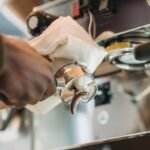 A hand holding a portafilter with a cloth, demonstrating backflushing an espresso machine.
