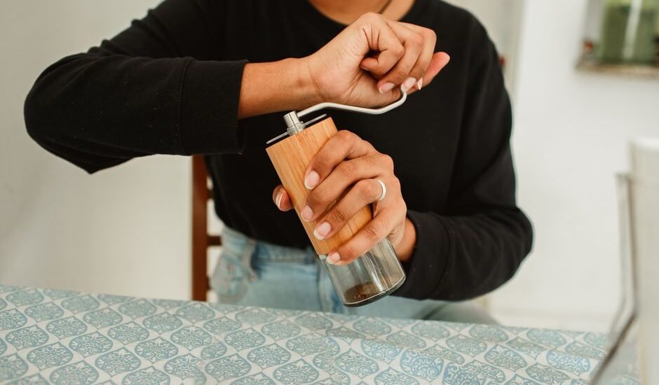 A person adjusting a manual coffee grinder, illustrating how to reset it.