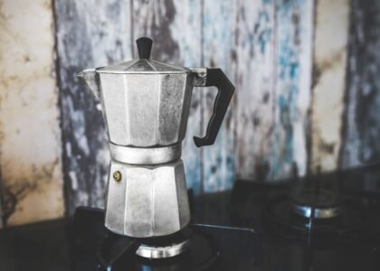 A moka pot sits on a stove, illustrating how to season it for better coffee.