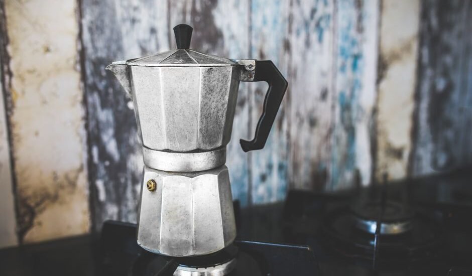 A moka pot sits on a stove, illustrating how to season it for better coffee.