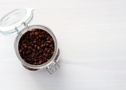 A glass jar filled with fresh coffee beans, illustrating how to store coffee.