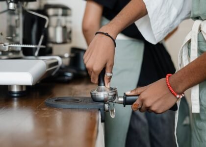 A person using an espresso tamper on a portafilter, demonstrating the technique for home brewing.