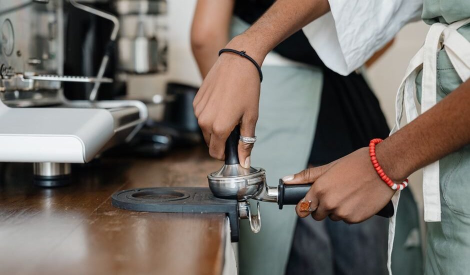 A person using an espresso tamper on a portafilter, demonstrating the technique for home brewing.