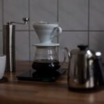 A coffee brewing setup showing a pour-over dripper, scale, and kettle, illustrating coffee-to-water ratio.